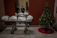 Mortuary workers take off their protective clothing at the entrance of a building decorated with a Christmas tree, after removing the body of person who allegedly died of COVID-19 in Barcelona, Spain, Wednesday, Dec. 23, 2020. (AP Photo/Emilio Morenatti)