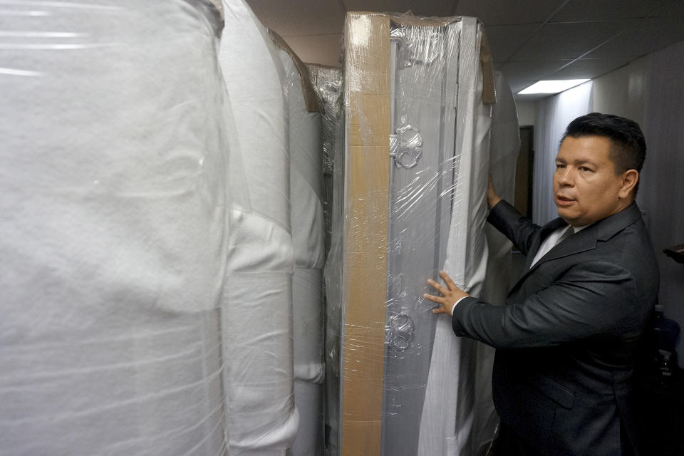 Azhar Dabdoub moves newly arrived caskets inside his funeral home, Wednesday, Sept. 7, 2022, in Tucson, Ariz. The caskets are customized with a small viewing window so families can see something of their relative, even if just a small belonging Dabdoub tapes to the glass. Last week he sent the bodies of five migrants to Guatemala and one to El Salvador. (AP Photo/Giovanna Dell'Orto)