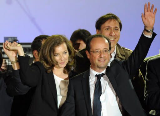 France's Socialist Party (PS) newly elected president Francois Hollande and his companion Valerie Trierweiler wave on stage at the Place de la Bastille after the announcement of the first official results of the French presidential second round