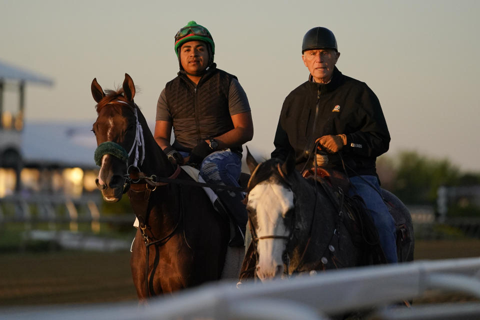 Horse trainer D. Wayne Lukas, right, rides atop Riff as he helps exercise rider Oscar Quevedo and Preakness entrant Secret Oath off the track after a morning workout ahead of the Preakness Horse Race at Pimlico Race Course, Wednesday, May 18, 2022, in Baltimore. Lukas could have entered the filly in the Black-Eyed Susan on Friday. Instead, the 86-year-old Hall of Fame trainer chose the Preakness for the Kentucky Oaks winner, who has done well facing off against male horses in previous opportunities. (AP Photo/Julio Cortez)