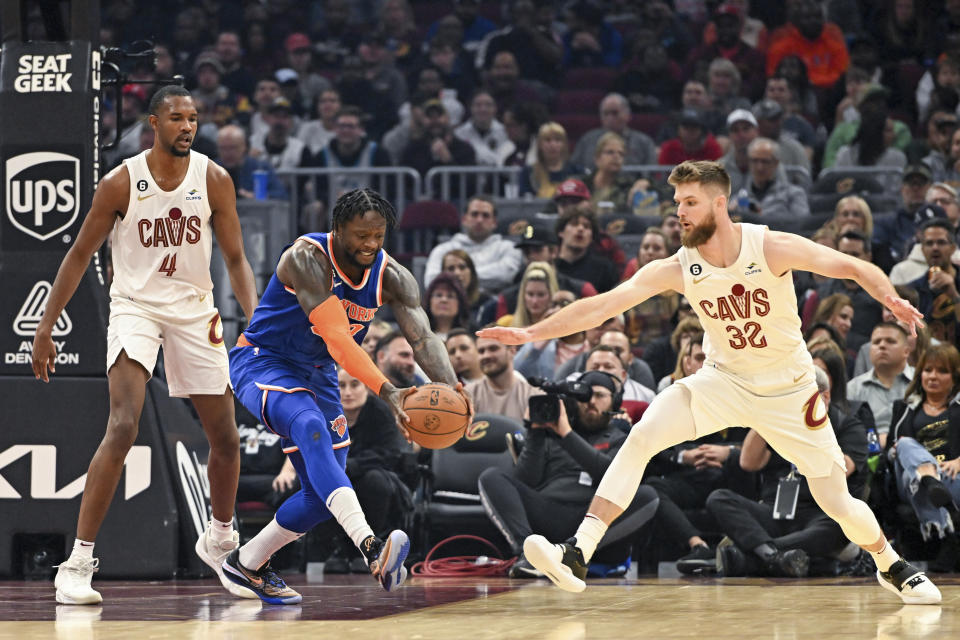 New York Knicks forward Julius Randle, second from left, grabs the ball against Cleveland Cavaliers forward Dean Wade (32) during the first half of an NBA basketball game, Sunday, Oct. 30, 2022, in Cleveland. (AP Photo/Nick Cammett)