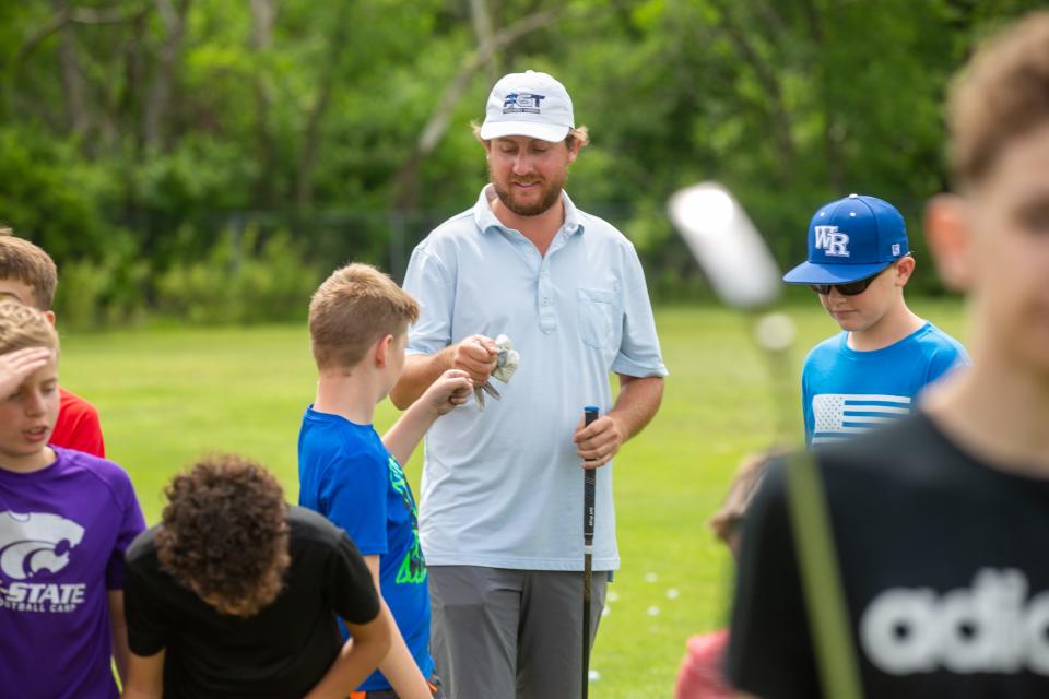 Andrew Beckler, a Washburn Rural and Washburn University alum, fist bumps young golfers at a summer camp Wednesday morning at Pure Golf Topeka.