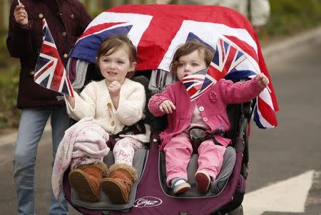 Children wave union flags as they wait for Britain's Queen Elizabeth and Prince Philip to arrive at Tweedbank Station in Scotland, Britain September 9, 2015. REUTERS/Phil Noble