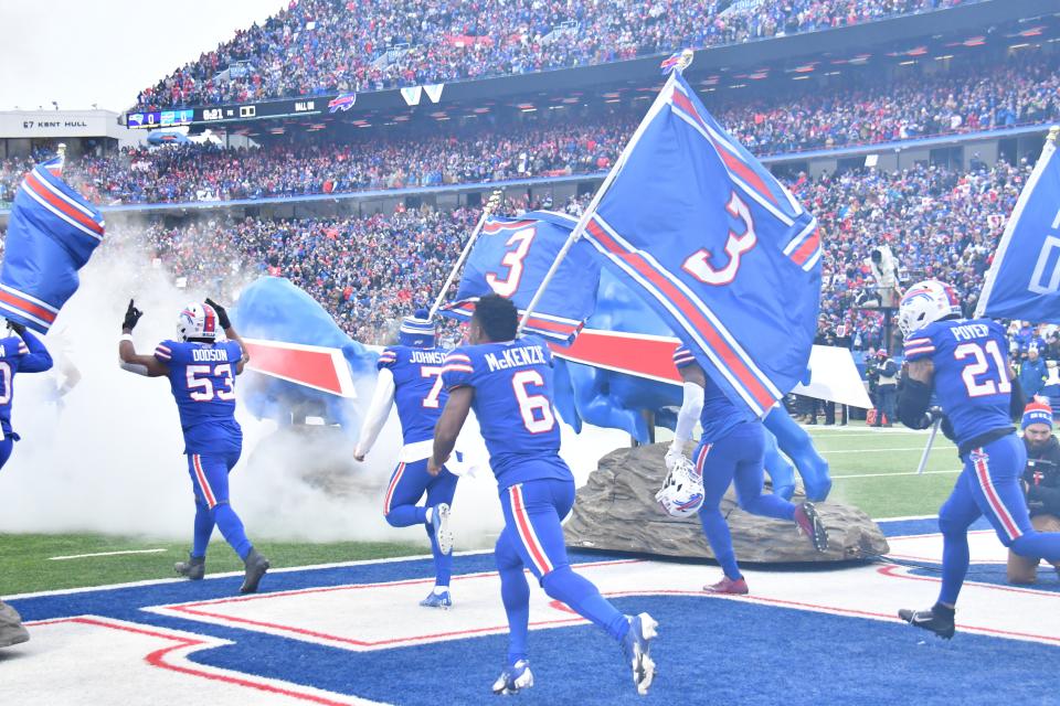 Buffalo Bills players enter the field before Sunday's game against the New England Patriots carrying No. 3 3 flags for Damar Hamlin.