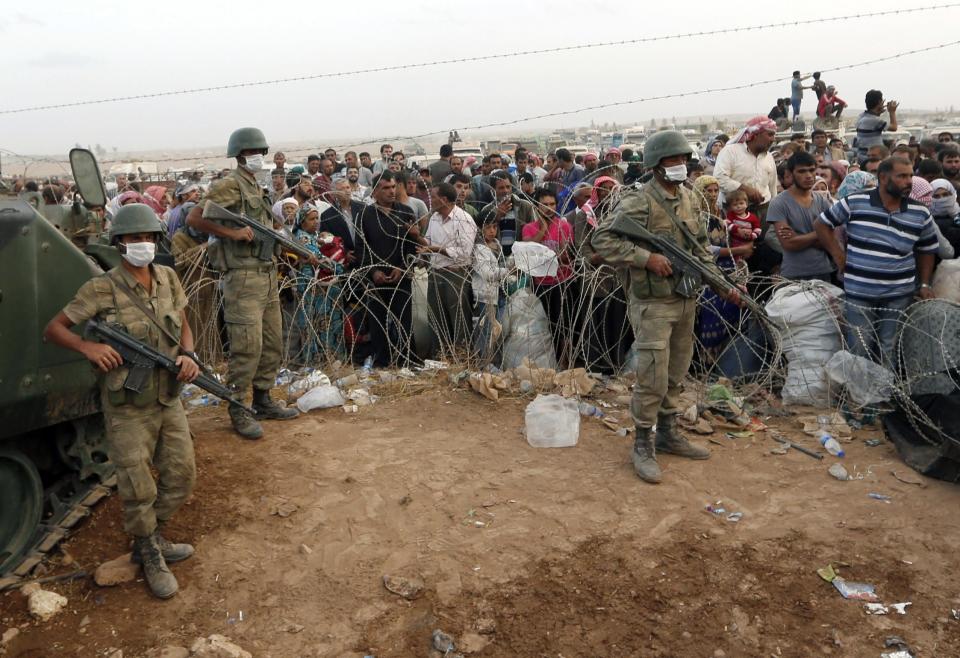 Turkish soldiers stand guard as Syrian Kurdish refugees wait behind the border fences to cross into Turkey near the southeastern town of Suruc in Sanliurfa province September 27, 2014. Turkish troops could be used to help set up a secure zone in Syria, if there was an international agreement to establish such a haven for refugees fleeing Islamic State fighters, President Tayyip Erdogan said in comments published on Saturday. Militants still held their positions around 10 kilometres west of Kobane inside Syria, the Reuters witness said, with Kurdish positions the last line of defence between the fighters and the town. Kobane sits on a road linking north and northwestern Syria and Kurdish control of the town has prevented Islamic State fighters from consolidating their gains, although their advance has caused more than 150,000 Kurds to flee to Turkey since last week. REUTERS/Murad Sezer (TURKEY - Tags: POLITICS CIVIL UNREST CONFLICT SOCIETY IMMIGRATION MILITARY TPX IMAGES OF THE DAY)