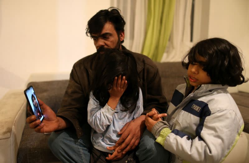 Frhan Hzam from Iraq and his children Hsan and Hubas speak with their mother who is in Germany, in a temporary home in the village near Velika Kladusa