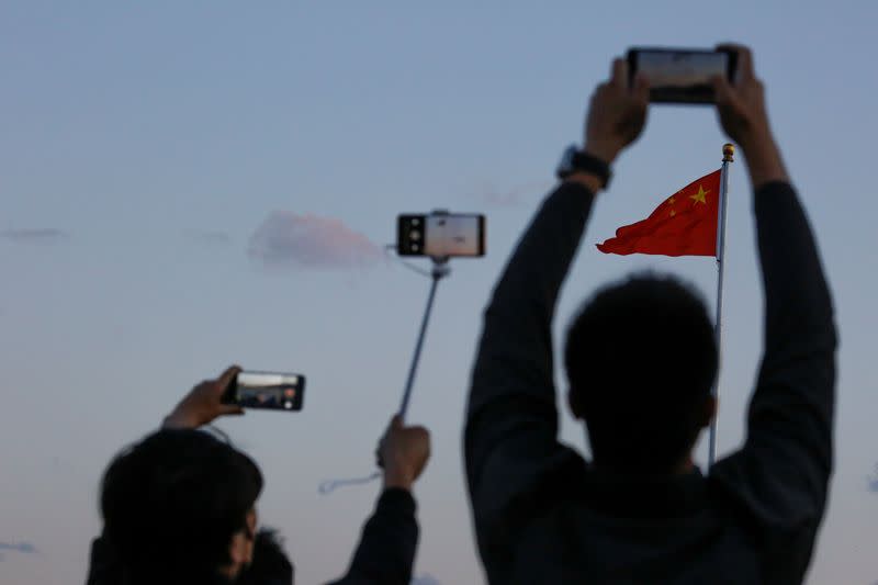 FILE PHOTO: People take pictures of the lowering ceremony of the Chinese national flag that is held daily at sunset in Tiananmen Square in Beijing