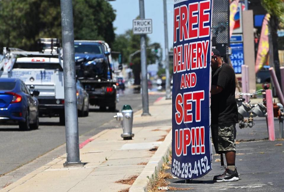 Gabriel Carpio trabaja en Blackstone Ave. ayudando a hacer publicidad para USA Furniture girando un letrero de un lado a otro durante todo el día. Fotografiado el miércoles 29 de mayo de 2024 en Fresno.