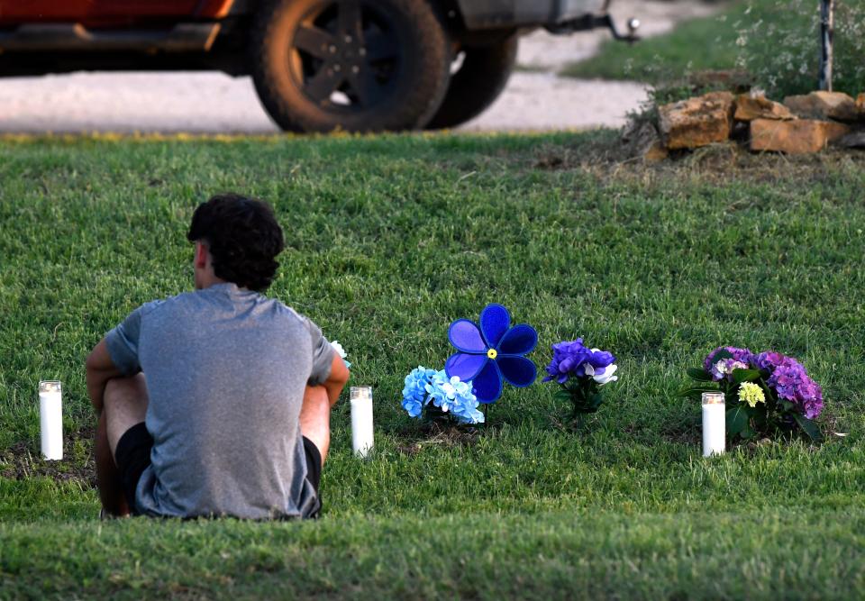 A student sits before three candles representing the teens who died at the intersection of West Third Street and Payton Road in Baird. Families, classmates and townspeople gathered to remember them during a memorial service May 7.