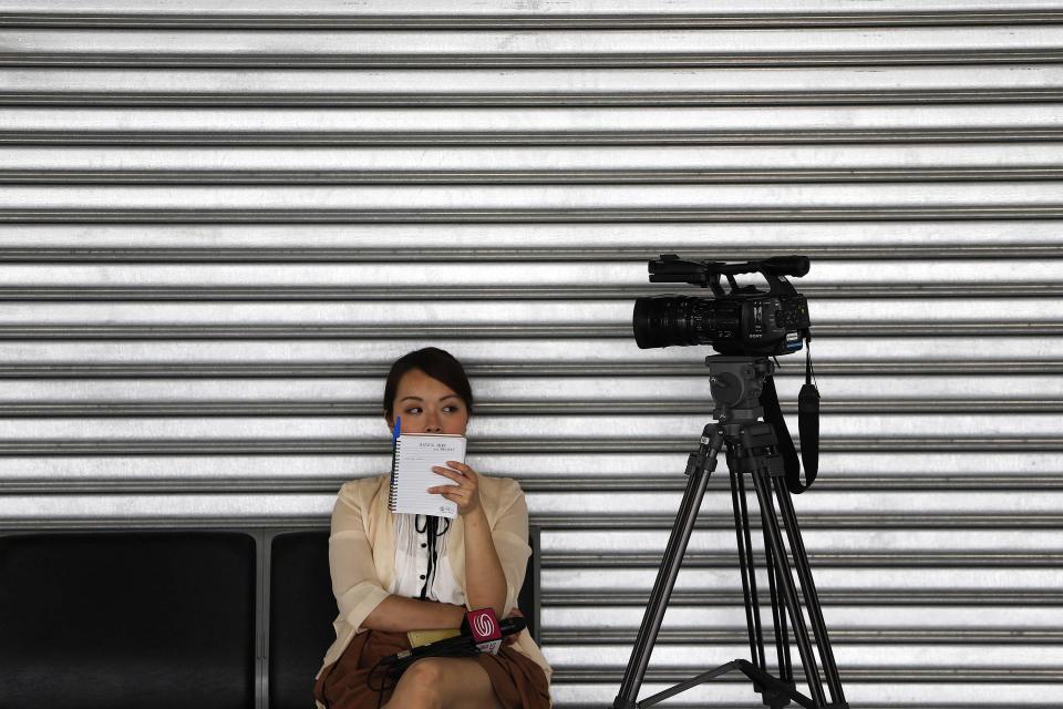 A reporter from China waits by her camera at the Kuala Lumpur International Airport