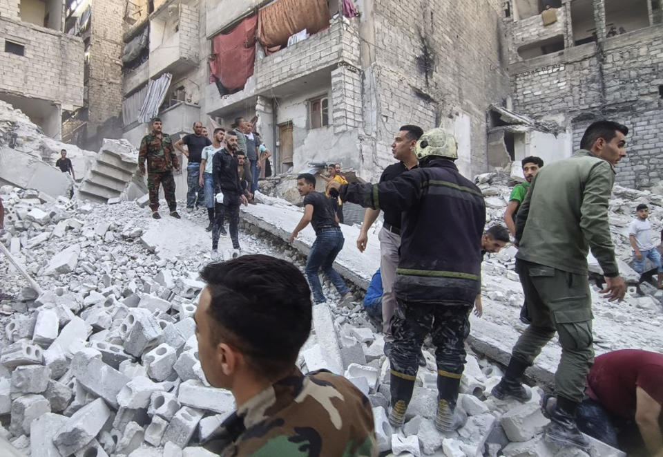 In this photo released by the Syrian official news agency SANA, Syrian Civil Defense workers and security forces work on the rubble of a destroyed building, in Aleppo, Syria, Wednesday, Sept. 7, 2022. A five-story building collapsed in Syria's northern city of Aleppo, killing several people, including three children, Syrian state television reported. (SANA via AP)