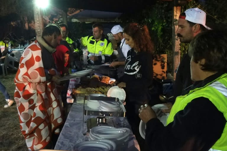 Volunteers serve dinner in a camp in Illica, central Italy on August 25, 2016 to victims of the earthquake in nearby Amatrice