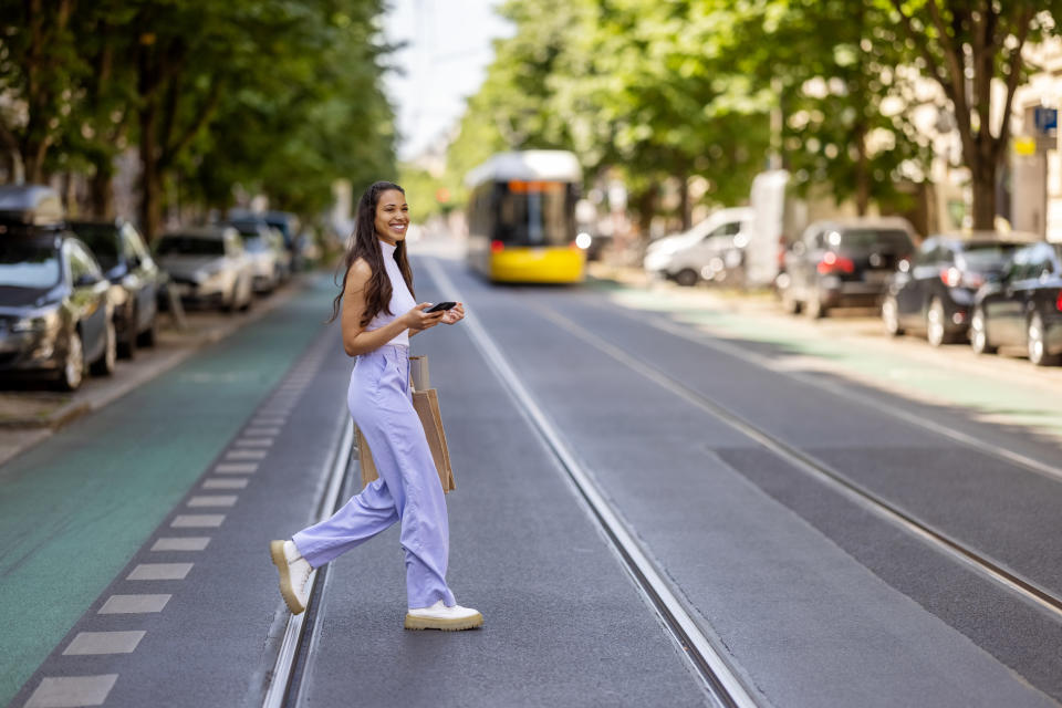 A young woman walking across the street and smiling