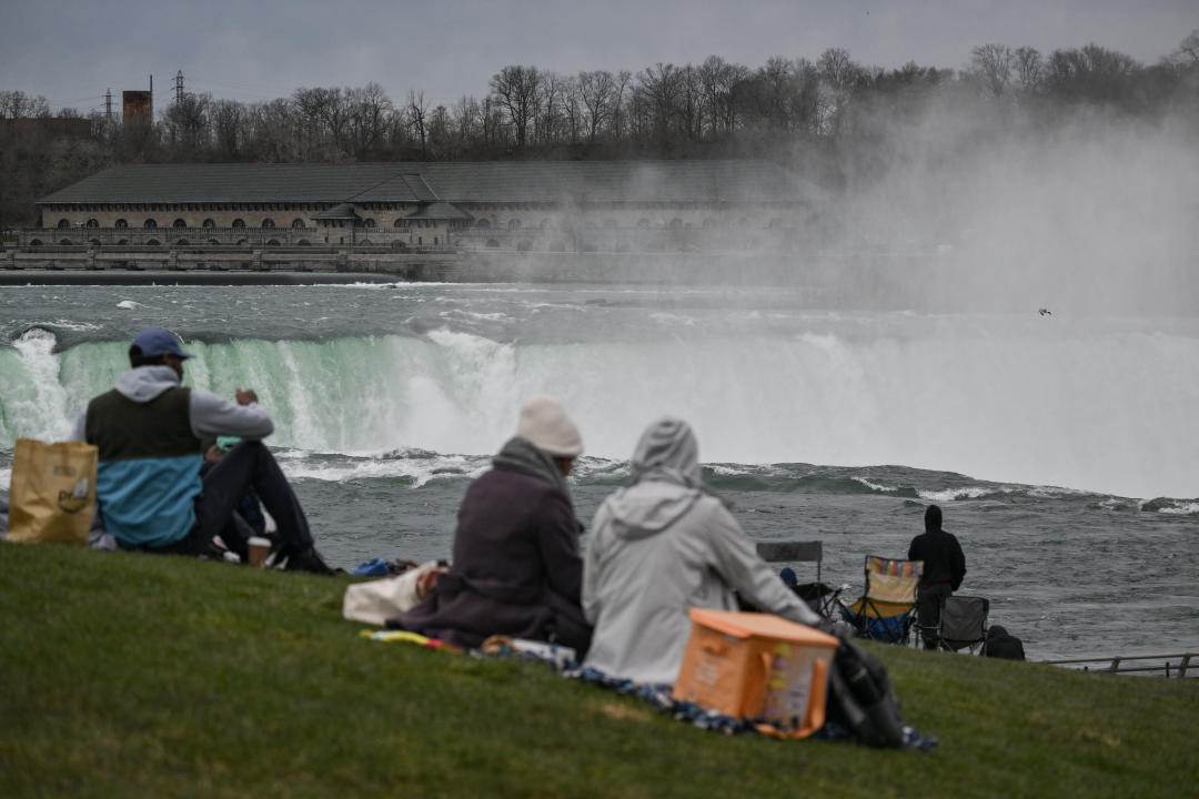 Verschillende mensen zitten op het gras bij de Niagara Falls.