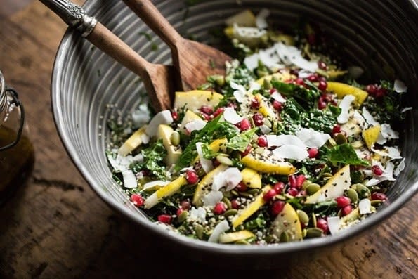 A salad bowl with chopped apples, coconuts, kale, pumpkin seeds, and chia seeds