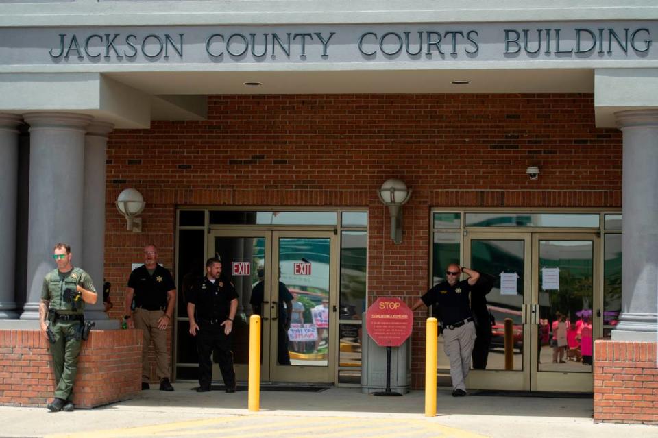 Members of law enforcement watch protestors from outside the Jackson County Courts building as a hearing in a chancery court case involving Heather Wyatt takes place inside on Thursday, July 18, 2024.