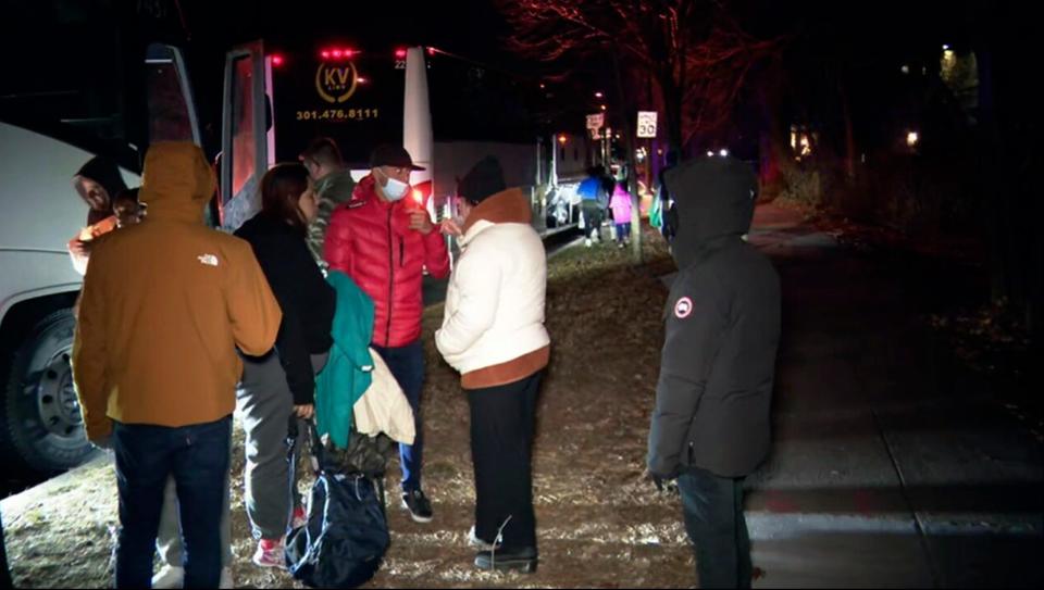 This image provided by WJLA shows migrant families as they get onto a bus to transport them from near the Vice President's residence to an area church after they arrived in Washington, Saturday, Dec. 24, 2022. Local organizers in Washington say three buses of recent migrant families arrived from Texas near the home in record-setting cold on Christmas Eve.