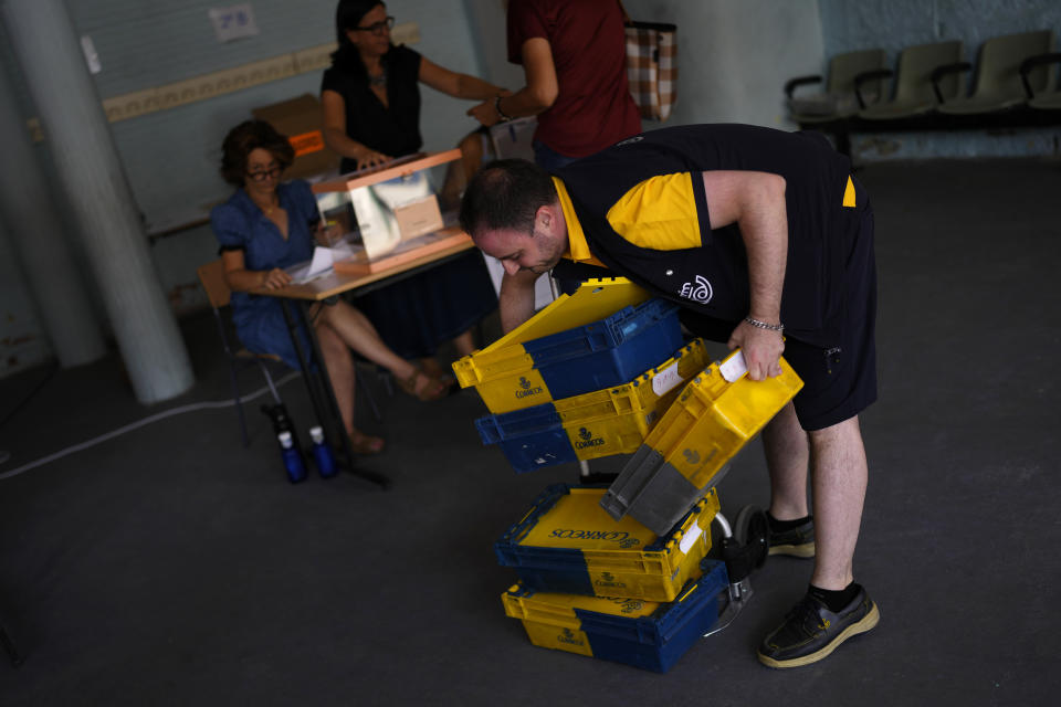 A post office worker delivers absentee votes for Spain's general election at a polling station in Madrid, Sunday, July 23, 2023. Sunday's election takes place at the height of summer, with millions of voters likely to be vacationing away from their regular polling places. But postal voting requests have soared, and officials have estimated a 70% election turnout. (AP Photo/Manu Fernandez)