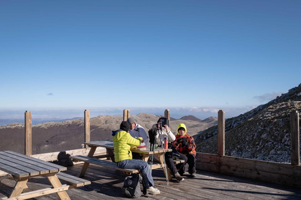 Visitors eat lunch at the top of a snowless Mount Miletto in Italy.<span class="copyright">Manuel Dorati</span>