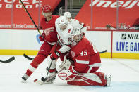 Detroit Red Wings goaltender Jonathan Bernier (45) stops a Carolina Hurricanes left wing Warren Foegele (13) shot as Detroit Red Wings defenseman Jon Merrill (24) defends in the third period of an NHL hockey game Saturday, Jan. 16, 2021, in Detroit. (AP Photo/Paul Sancya)