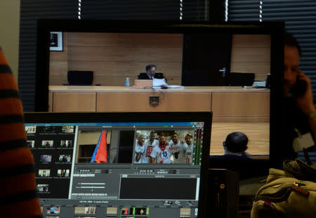 Jose Francisco Cobo, magistrate from the High Court of Navarra, is seen on screen as he delivers a nine-year prison sentence on five men accused of the multiple rape of a woman during Pamplona's San Fermin festival in 2016, in front of a monitor screen showing a picture of the accused, in Pamplona, Spain, April 26, 2018. REUTERS/Vincent West