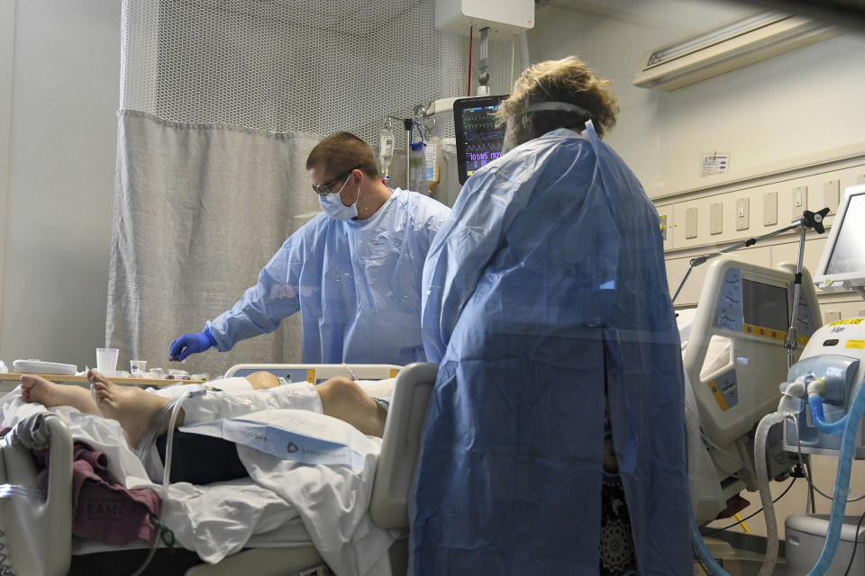 Nurse Jesse Phelps, left, works on a COVID-19 patient as a family member looks on at East Alabama Medical Center in the intensive care unit Thursday, Dec. 10, 2020, in Opelika, Ala. The medical center faces a new influx of COVID-19 patients as the pandemic intensifies. (AP Photo/Julie Bennett)