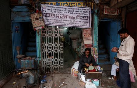 A man sells cigarettes and tobacco as a banner is hanging at the entrance of a closed garments market during a protest against the implementation of the goods and services tax (GST) on textiles, in the old quarters of Delhi, India June 29, 2017. REUTERS/Adnan Abidi