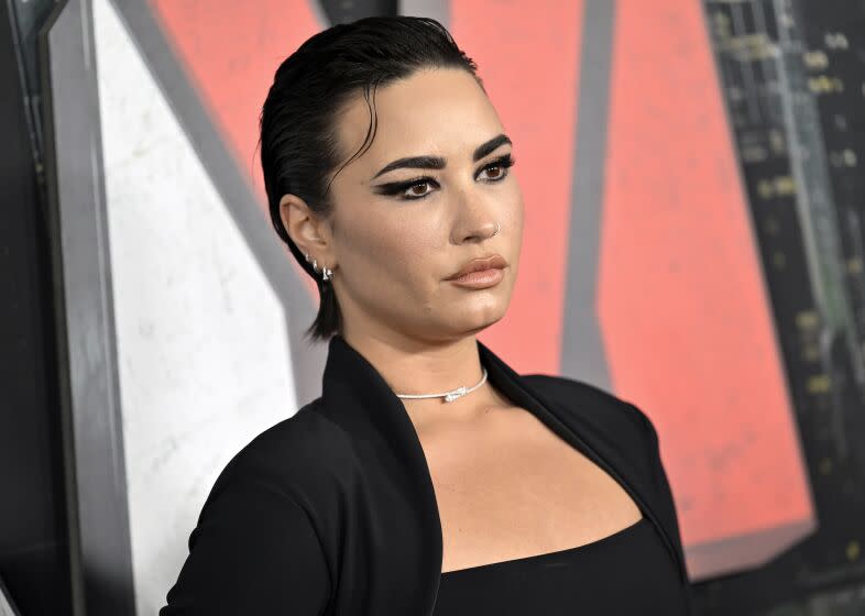 Demi Lovato poses in an all black outfit and a silver choker.
