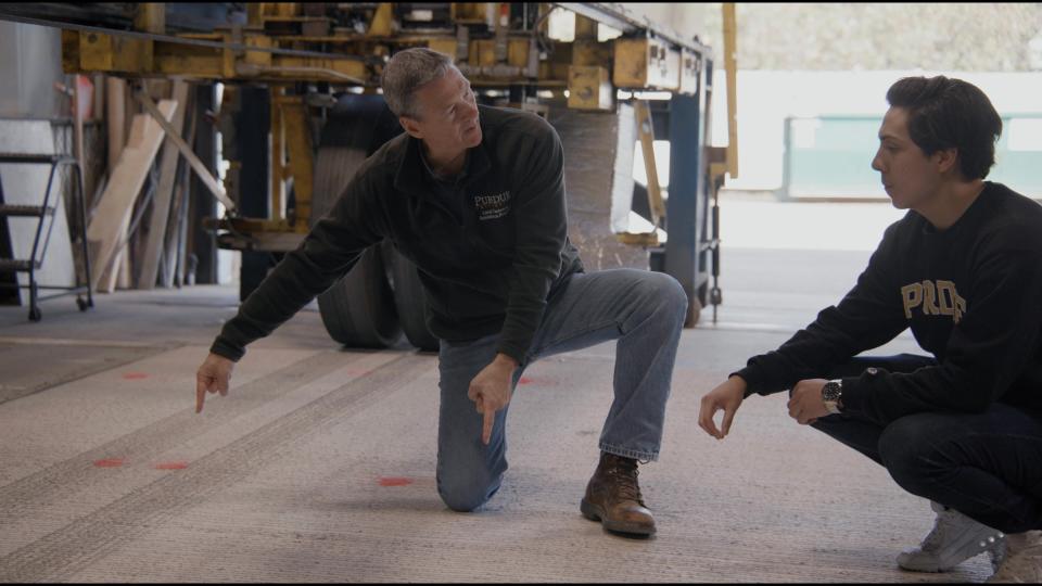 image of two men kneeling down to examine a section of pavement