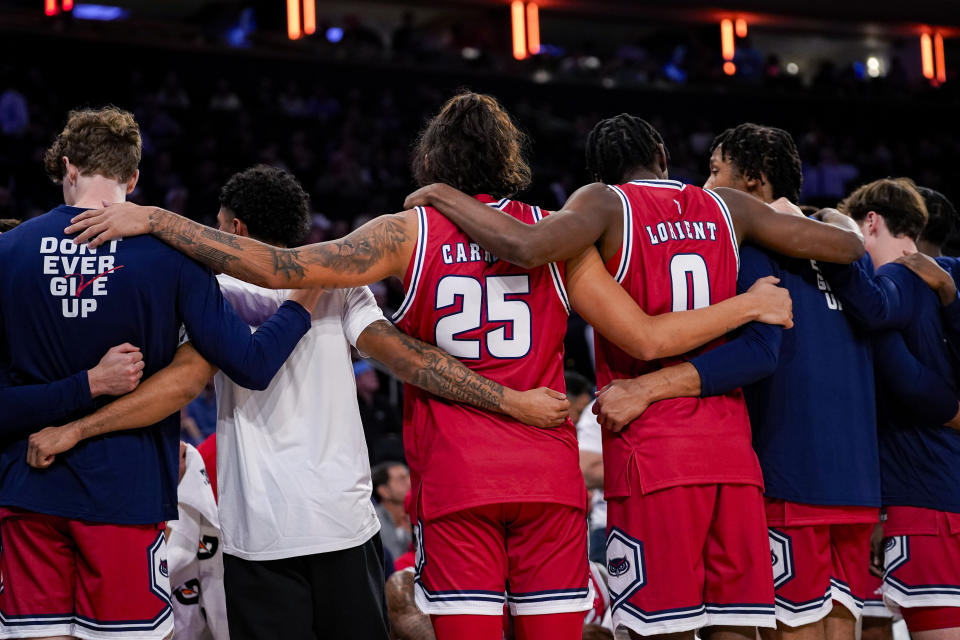 Florida Atlantic's Tre Carroll (25) and Brenen Lorient (0) huddle with teammates during a timeout in the second half of an NCAA college basketball game against Illinois in New York, Tuesday, Dec. 5, 2023. (AP Photo/Peter K. Afriyie)