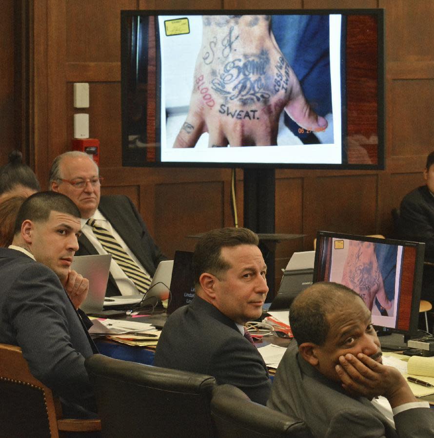 From left, with a photograph of former New England Patriots football player Aaron Hernandez's right hand projected behind them, defense attorneys Jose Baez and Ronald Sullivan listen to assistant district attorney Mark Lee during Hernandez's double murder trial in Suffolk Superior Court in Boston on Friday, March 17, 2017. Hernandez is on trial for the July 2012 killings of Daniel de Abreu and Safiro Furtado who he encountered in a Boston nightclub. The former NFL player is already serving a life sentence in the 2013 killing of semi-professional football player Odin Lloyd. (Chris Christo/The Boston Herald via AP, Pool)