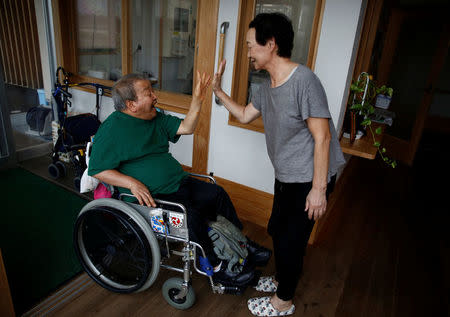 Congenital Minamata disease patient Isamu Nagai high-fives a caretaker as he arrives at Oruge-Noa, a group care home for disabled people including Minamata disease patients, in Minamata, Kumamoto Prefecture, Japan, September 13, 2017. REUTERS/Kim Kyung-Hoon
