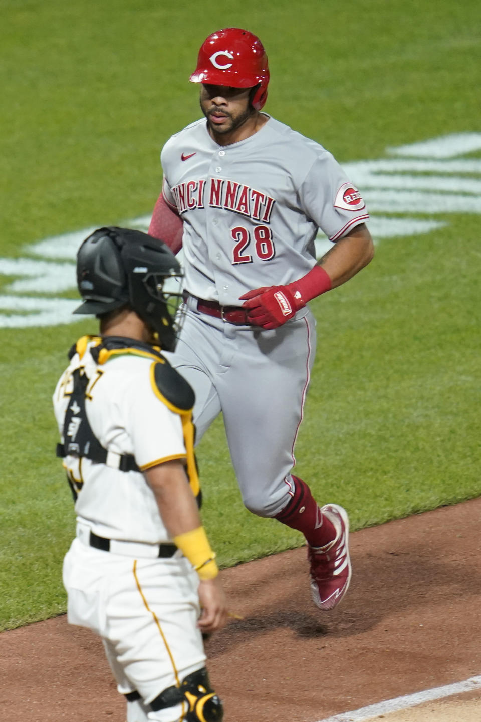 Cincinnati Reds' Tommy Pham (28) scores next to Pittsburgh Pirates catcher Michael Perez on a Colin Moran hit during the eighth inning of a baseball game Thursday, May 12, 2022, in Pittsburgh. (AP Photo/Keith Srakocic)