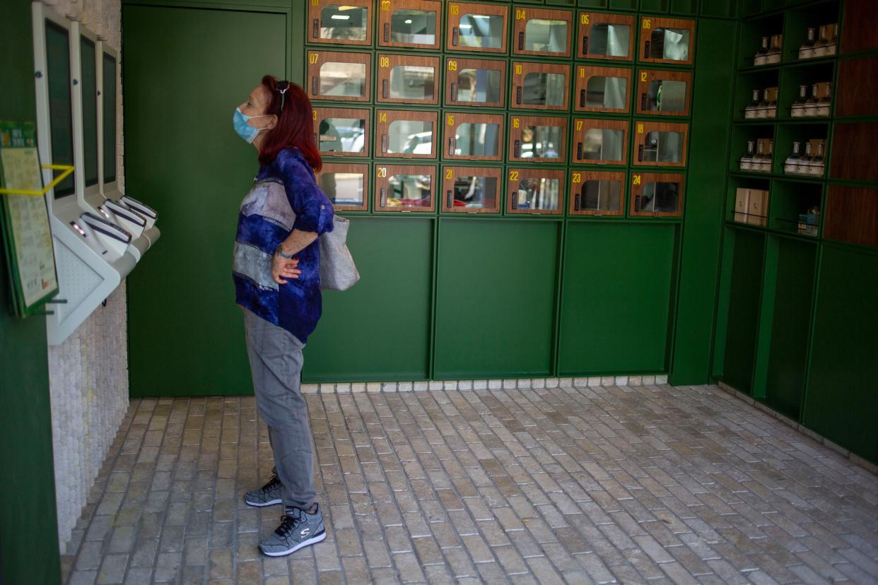 A customer reads the menu at Go noodles where her order will be served in one of the glass-paned lockers seen behind her in Tel Aviv, Israel on Thursday, July 16, 2020. The coronavirus crisis and its economic impact have forced many small businesses and restaurants to shut their doors in recent months, but Tel Aviv's Go Noodles opened a new branch last week that features digital-only ordering and pickup from lockers.