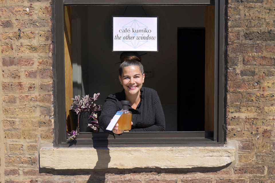 CORRECTS SPELLING OF NAME TO JULIA MOMOSE, INSTEAD OF JULIE MOMOSA - Julia Momose poses for a portrait at the serving window with a "cocktail to go" at the Kumiko bar in Chicago's West Loop neighborhood Friday, Aug. 14, 2020. Momose, a longtime bartender and co-owner of Kumiko, shut the bar on March 16 due to the pandemic, spending the next three months collecting petition signatures and lobbying the city to allow cocktails to go. That measure passed on June 17, and she sold the first to-go cocktail in Chicago that day. (AP Photo/Charles Rex Arbogast)