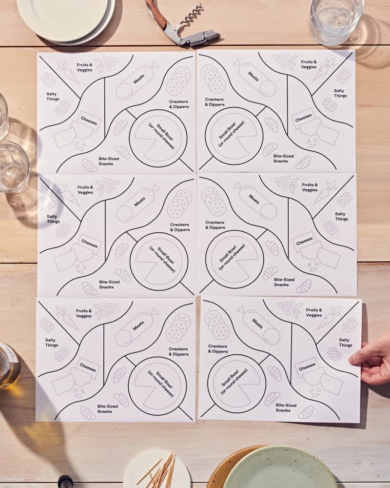 6 grazing board 8.5x11 template sheets of paper that show you how to place snacks, cheese, meat, fruit etc in order to have a party. On table with plates, glasses around