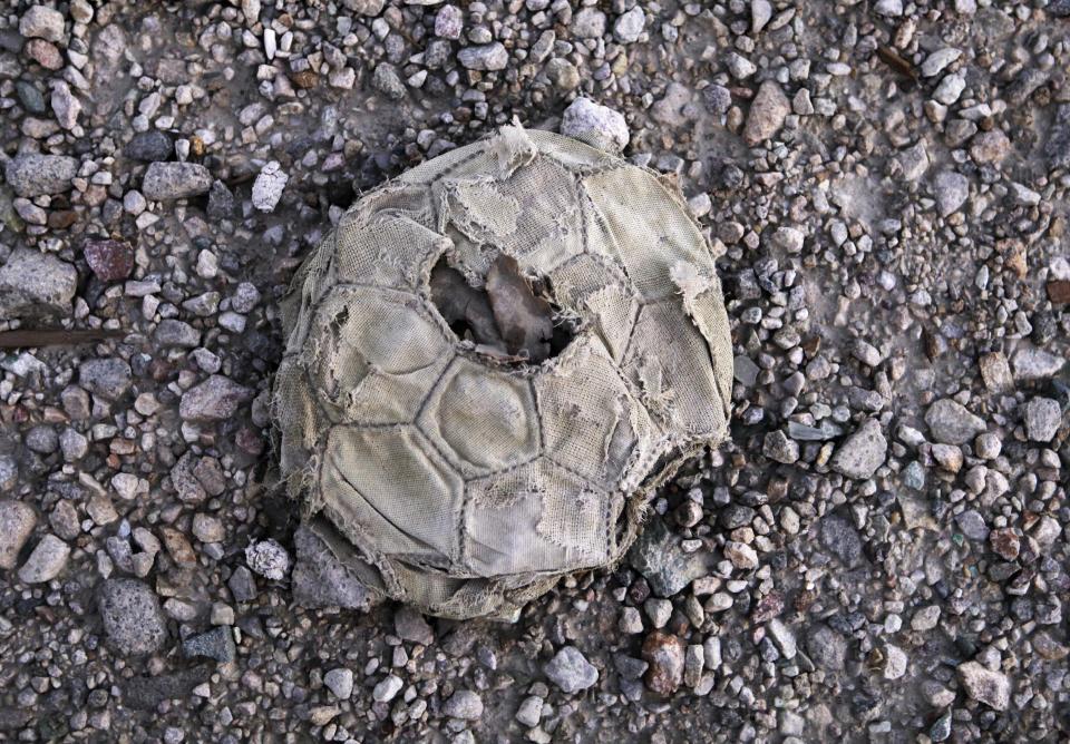 In this Sept. 25, 2012 photo, a deflated soccer ball lays in a street in an area that used to be the town where miners lived at the Chuquicamata copper mine in Atacama desert in northern Chile. The town was moved as the mine grew. Experts say that by 2019 the Chuquicamata copper mine will be unprofitable, so state-owned mining company Codelco is trying to head off closure by converting the open pit into the world's largest underground mine. Codelco believes the mine still has much more to give, with reserves equal to about 60 percent of all the copper exploited in the mine's history still buried deep beneath the crater. (AP Photo/Jorge Saenz)