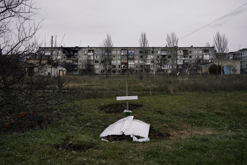 A makeshift grave in grass in front of a grey building