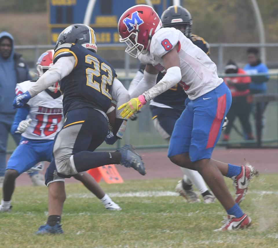 Robert Arnold of Monroe punches the ball away from Wayne running back Elijah Mackey.