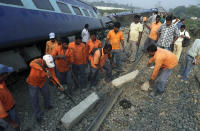Railway workers remove debris from a track where a train derailed near Jagiroad Railway Station, about 90 kilometers (56 miles) east of Gauhati, India, Wednesday, April 16, 2014. According to a Northeast Frontier Railway officer, dozens of people were injured when the train jumped the tracks and derailed early Wednesday. (AP Photo/Anupam Nath)