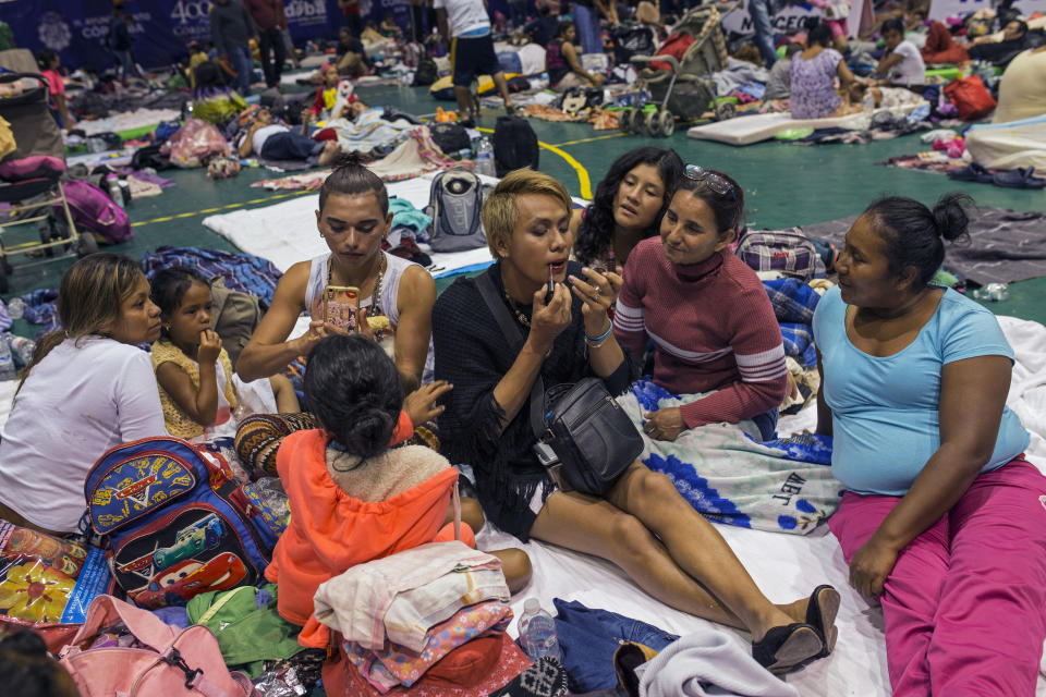 In this Nov. 4, 2018 photo, two transgender women who are part of a group of 50 or so LGBTQ migrants traveling with the migrant caravan hoping to reach the U.S. border, apply face makeup at a shelter in Cordoba, Mexico. Sticking out among the crowd for their bright clothing and makeup, the group has suffered verbal harassment, especially from men. (AP Photo/Rodrigo Abd)
