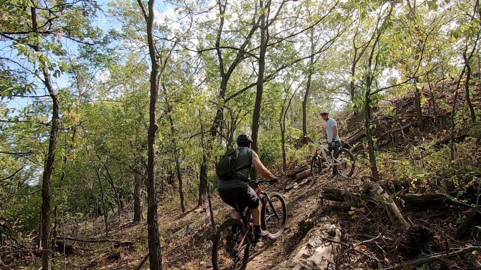 Bicycle Pedaler owner Tyler Branine, right, cheers on a mountain biker on the trail at El Dorado State Park. More than 50 volunteers put in more than 1,000 hours of work on the first 5.5 miles of intermediate trails. There is more than 1,000 feet of elevation gain on the trails.