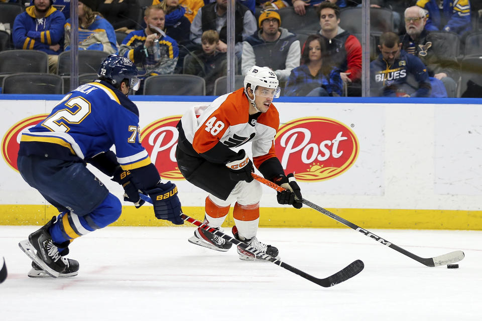 Philadelphia Flyers' Morgan Frost (48) controls the puck under pressure from St. Louis Blues' Justin Faulk (72) during the third period of an NHL hockey game Monday, Jan. 15, 2024, in St. Louis. (AP Photo/Scott Kane)