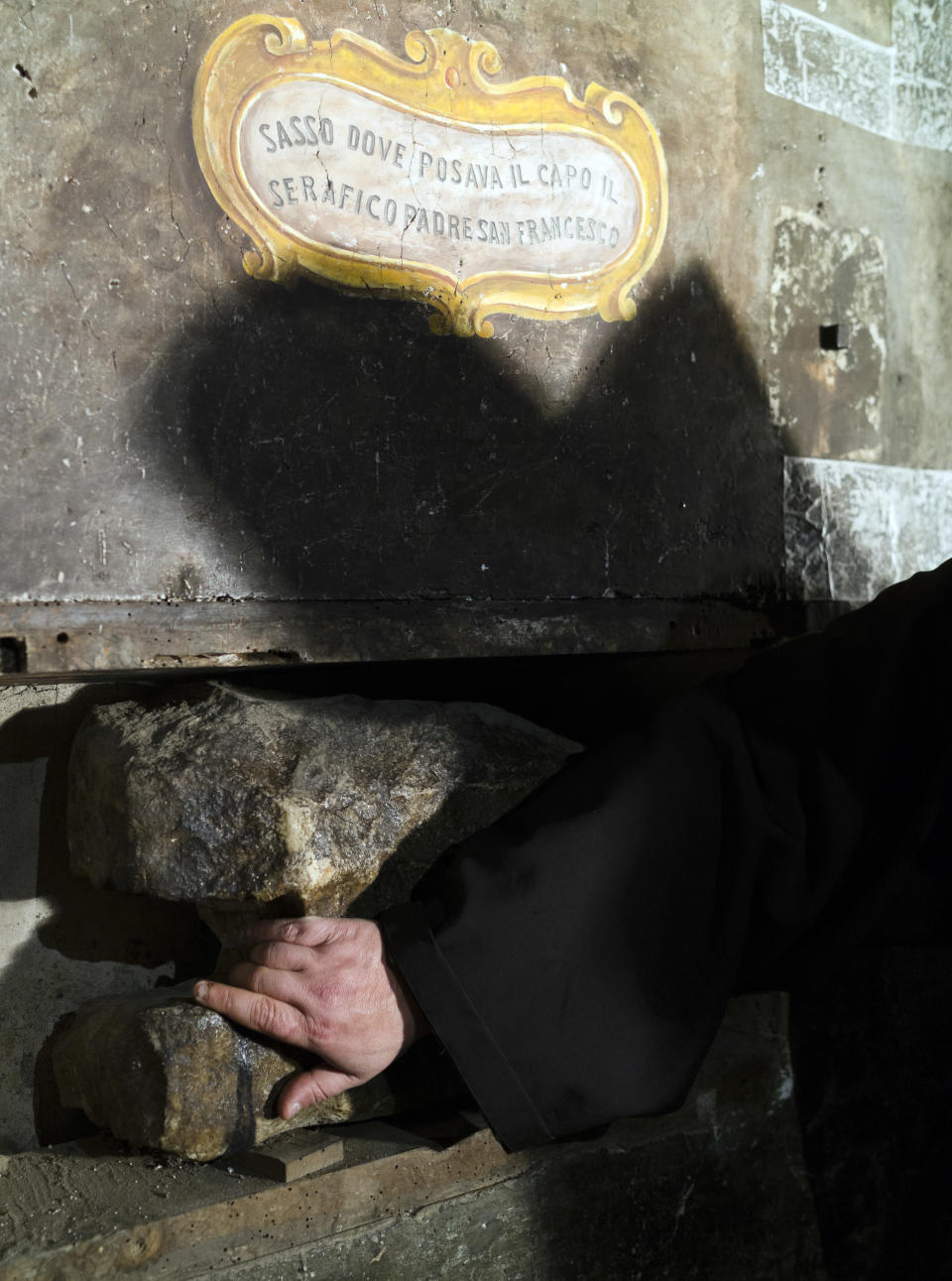 The head of the Franciscan convent of St. Francesco a Ripa, Friar Stefano Tamburo casts his shadow on a stone believed to be used by St. Francis of Assisi as a pillow when visiting the convent in Rome, Friday, Feb. 28, 2014. The inscription reads in Italian: "Stone where the Serafic Father St. Francis would rest his head". The friars who run the St. Francis a Ripa church in Rome's Trastevere neighborhood are launching a Kickstarter online fundraising campaign Tuesday, March 11, 2014, to try to raise the $125,000 to restore the tiny cell upstairs from the sacristy where St. Francis stayed, The Associated Press has learned. Rather than ask for funding from the Italian government, which owns the church and is responsible for its upkeep, the friars decided on this more democratic crowdfunding initiative thinking it more in keeping with the Franciscan tradition of seeking alms for just what they need, spreading the faith as they beg, and making sure the poor are the priority. (AP Photo/Domenico Stinellis)