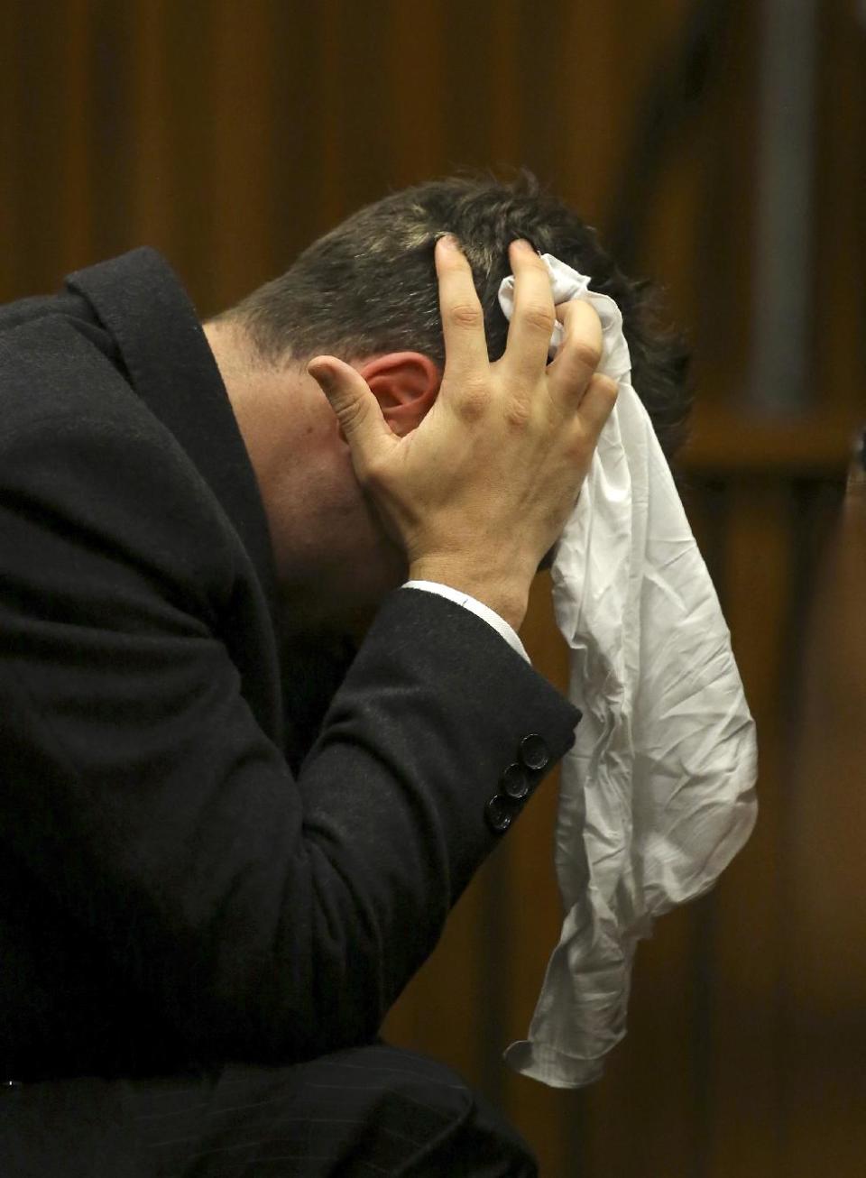 Oscar Pistorius covers his head with a handkerchief after he had reached for a bucket at his feet while listening to cross questioning about the events surrounding the shooting death of his girlfriend Reeva Steenkamp, in his second week in court during his trial in Pretoria, South Africa, Monday, March 10, 2014. Pistorius is charged with the shooting death of his girlfriend Steenkamp, on Valentines Day in 2013. (AP Photo/Siphiwe Sibeko, Pool)