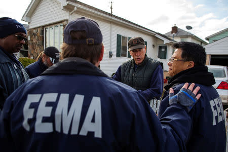 FILE PHOTO: Representatives from FEMA speak with a resident of the Staten Island borough neighborhood of New Dorp Beach about registering with the agency for financial assistance to help recover from the storm surge of Hurricane Sandy in New York, NY, U.S., November 15, 2012. REUTERS/Lucas Jackson/File Photo