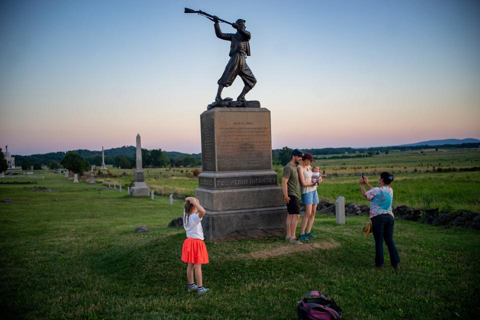 Several people take pictures at the monument at Gettysburg.