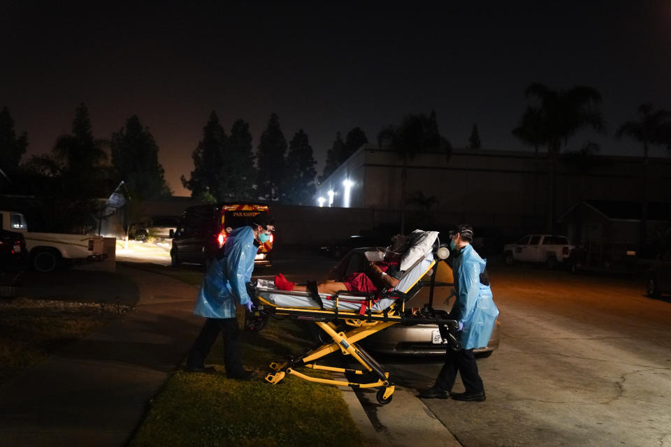 Emergency medical technicians Joshua Hammond, left, and Thomas Hoang, of Emergency Ambulance Service, transport a COVID-19 patient to an ambulance in Placentia, Calif., Friday, Jan. 8, 2021. For EMTs Thomas Hoang and Joshua Hammond, the coronavirus is constantly close. COVID-19 has become their biggest fear during 24-hour shifts in California's Orange County, riding with them from 911 call to 911 call, from patient to patient. (AP Photo/Jae C. Hong)