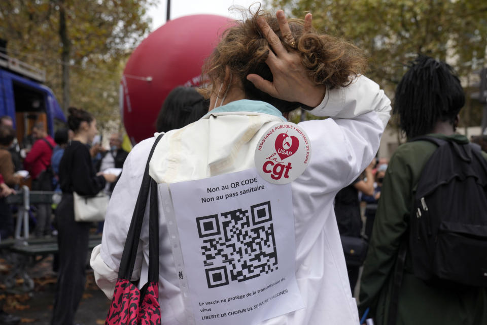 A medical worker wearing a paper reading "No to QR code, No to Health Pass , the vaccin does not prevent for the virus transmission, Freedom to choose to be vaccinated" during a protest gathering outside the Health Ministry in Paris, Tuesday, Sept. 14, 2021 against a law requiring them to get vaccinated by Wednesday or risk suspension from their jobs. The law is aimed at protecting patients from new surges of COVID-19. Most of the French population is vaccinated but a vocal minority are against the vaccine mandate. (AP Photo/Francois Mori)