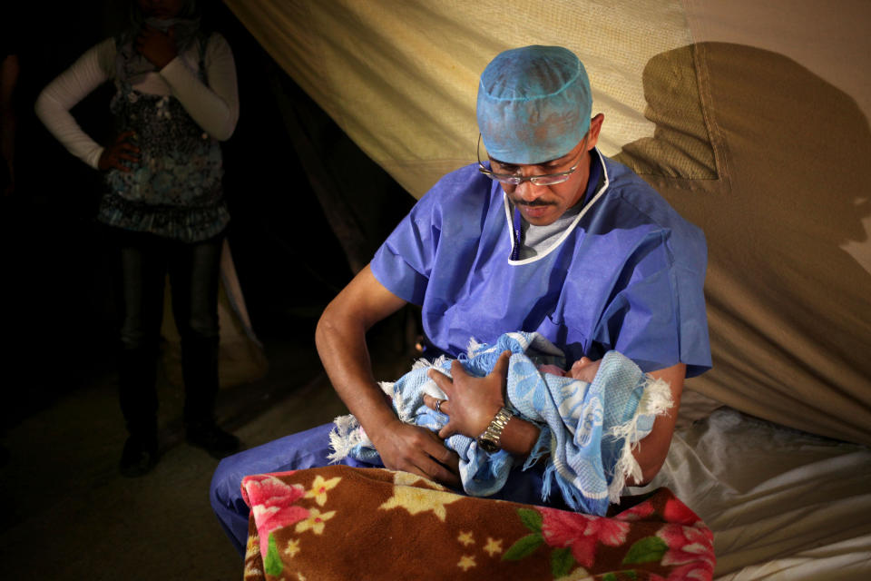 FILE - In this Monday, May 6, 2013 file photo, an obstetrician holds a baby after delivery at the Moroccan field hospital in Zaatari refugee camp near the Syrian border, in Mafraq, Jordan. An international charity organization Save Children has warned Monday, March 10, 2014 of a health care disaster in Syria with newborns dying in hospital incubators during power cuts and children having their limbs amputated for lack of alternative treatment. (AP Photo/Mohammad Hannon, File)
